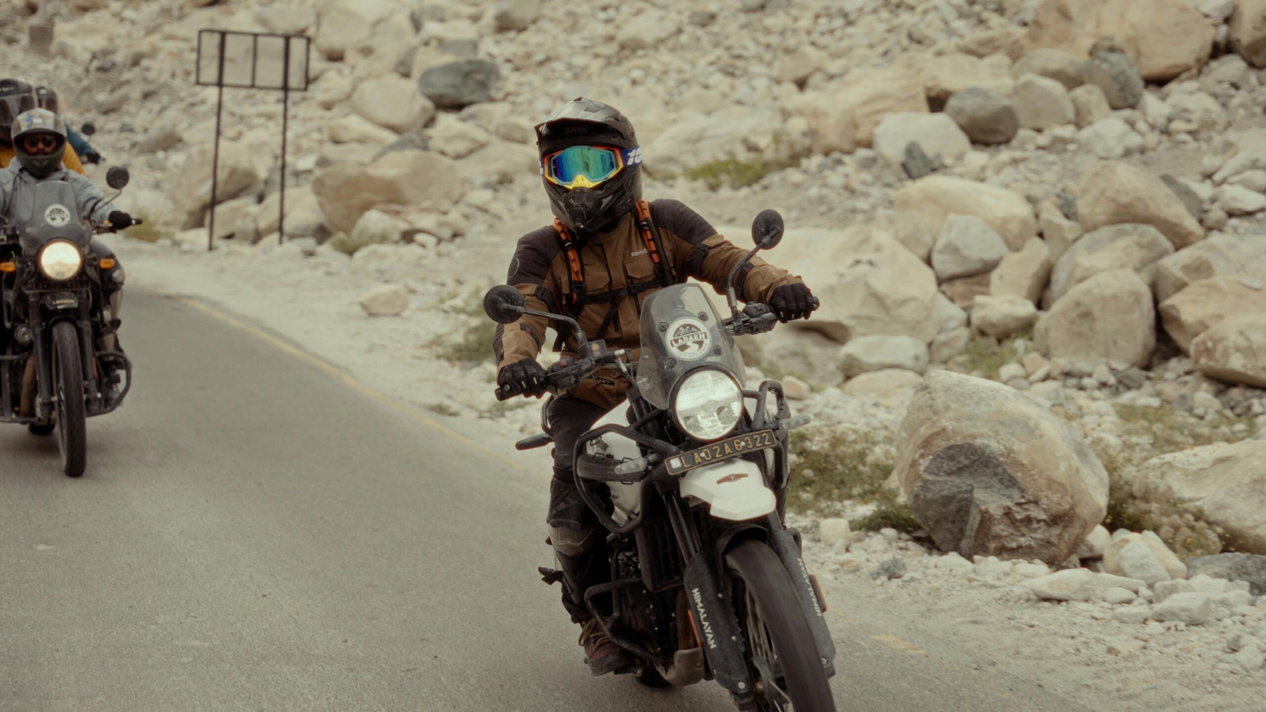 Motorcyclists in protective gear navigating a rocky road on their adventure.