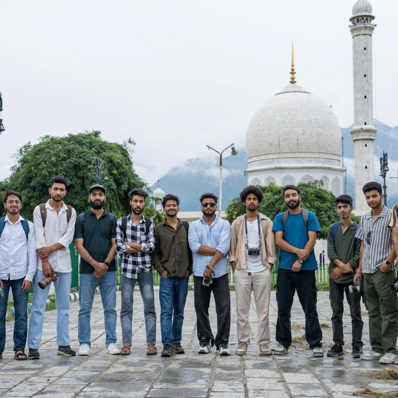A group of young adults in front of an iconic mosque in Srinagar, showcasing cultural diversity and friendship.